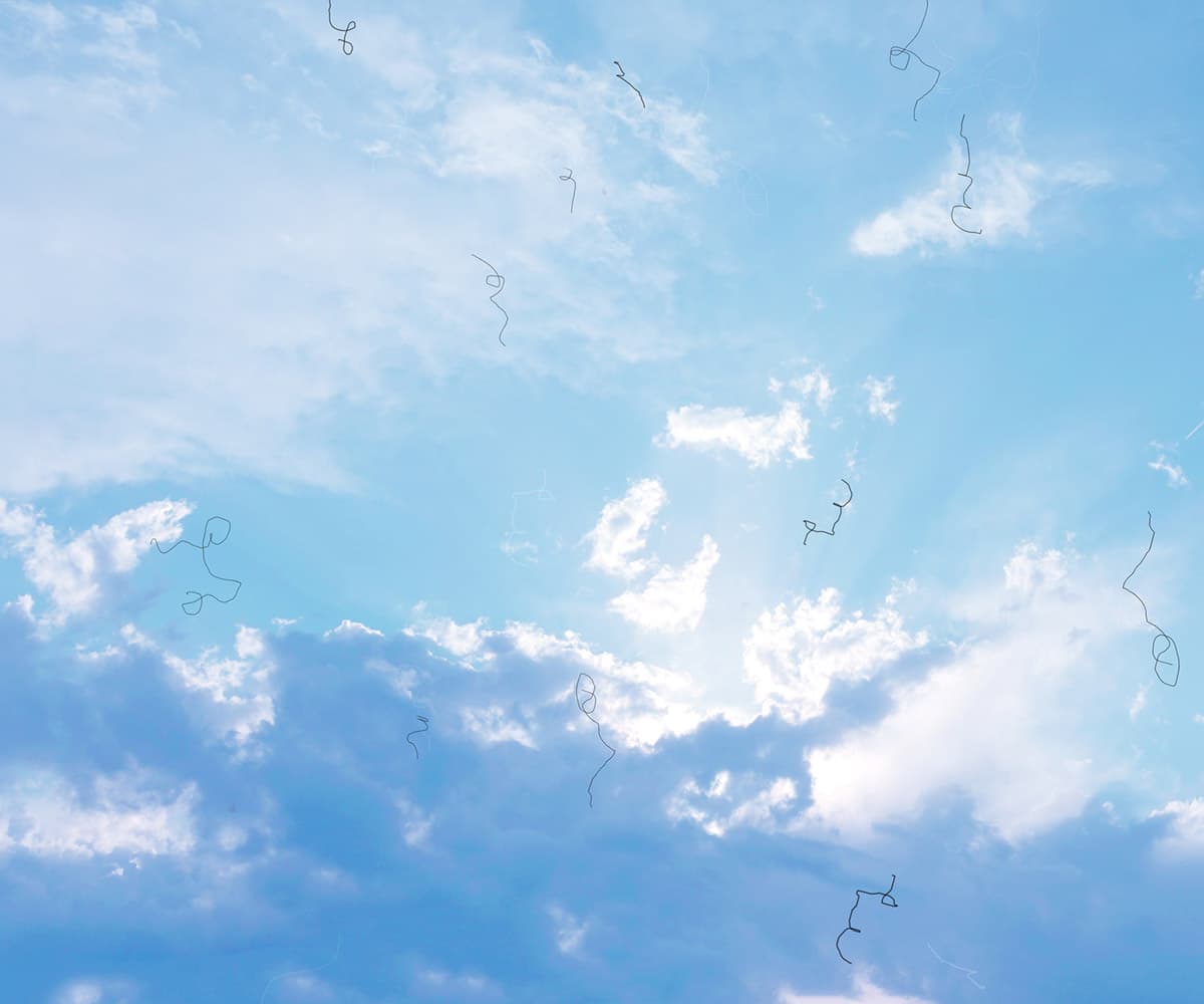 A bright blue sky with scattered clouds and thin, wispy strands floating across it, illuminated by sunlight peeking through the clouds.